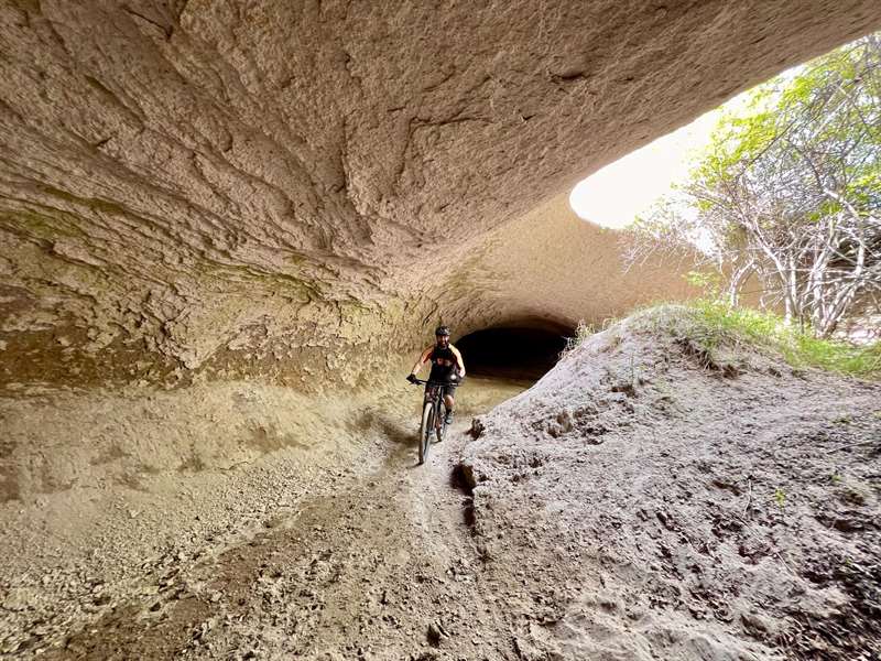 Mountainbiker op een pad onder een overhangende rotswand