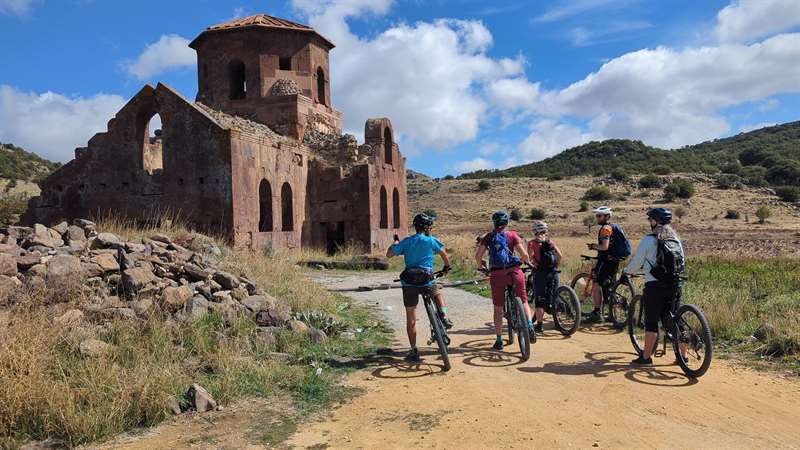 Fietsers bij de ruïne van een oude stenen kerk