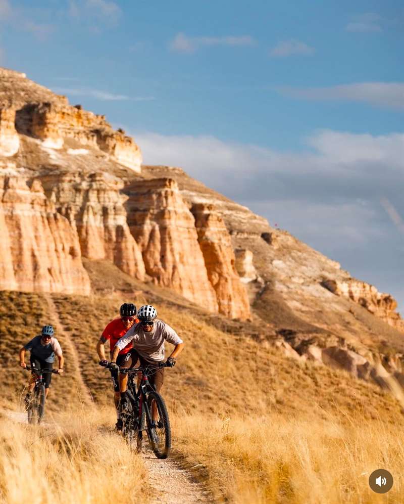 Mountainbikers op een zandpad langs witte rotswanden