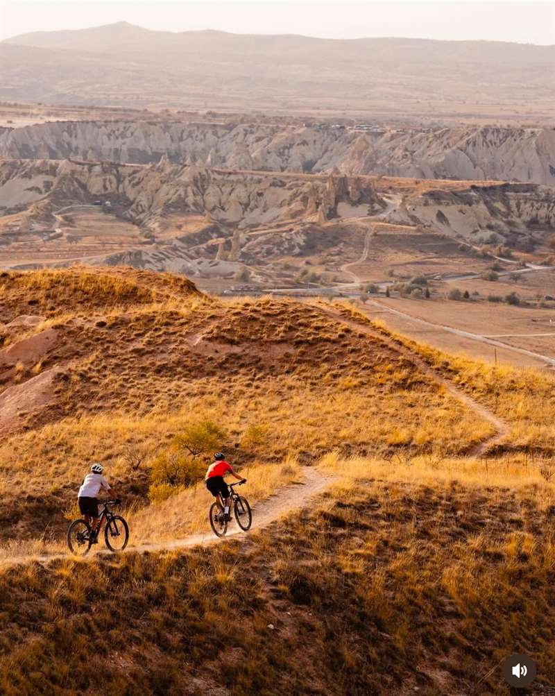Twee mountainbikers op een singletrack door goudkleurige heuvels